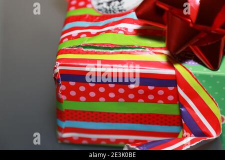 Opening a brightly colored gift that has a red bow on it Stock Photo