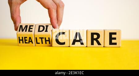 Medicare or healthcare symbol. Doctor turns cubes, changes the word 'healthcare' to 'medicare'. Beautiful yellow table, white background. Copy space. Stock Photo