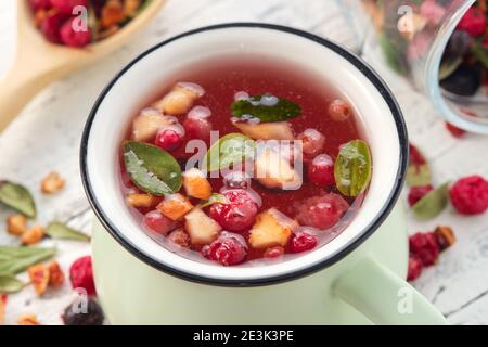 Cup of healthy fruit tea with apples, orange, red and black currant berries. Stock Photo