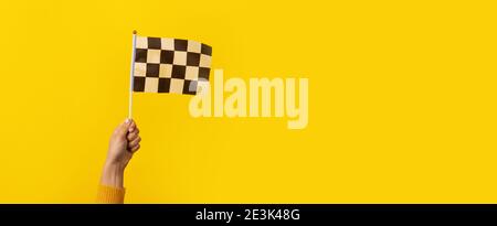 checkered flag in hand over yellow background, panoramic image Stock Photo