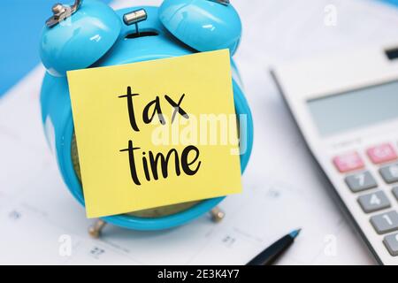 Tax Time Written on Sticky Note, Sticking on Alarm Clock. Stock Photo