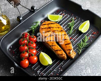 grilled steak fish salmon, trout in a grill pan, spices, rosemary, tomato Stock Photo
