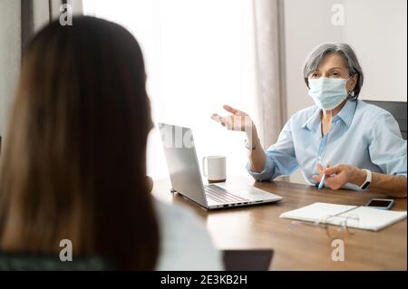 Elder female manager in a face mask interviewing Stock Photo