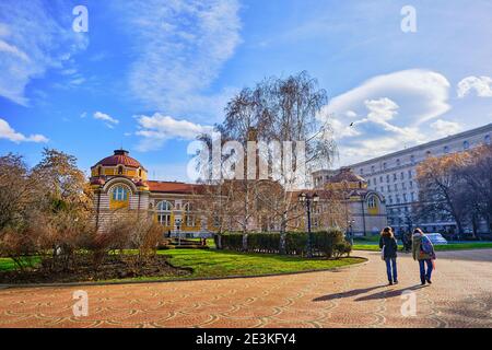 Regional History Museum and Central Mineral Baths Sofia and people walking around the park in front of it. Sofia. Bulgaria. 06.01.2021. Stock Photo