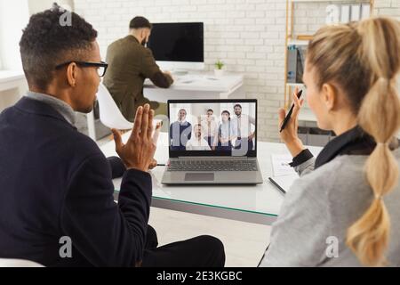 Young diverse business people waving hands to their coworkers during video conference Stock Photo
