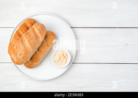Bread and butter in a flat plate on a white wooden background. Stock Photo