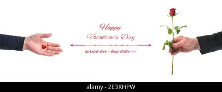 Hands of woman and man want to give each other a heart and a rose during the corona virus pandemic, text Happy Valentines Day, spread love keep distan Stock Photo