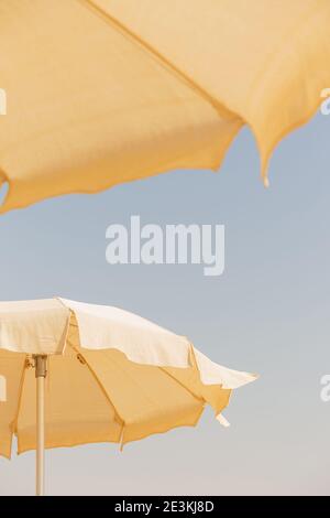 Two beige cotton beach umbrellas against a blue sky Stock Photo