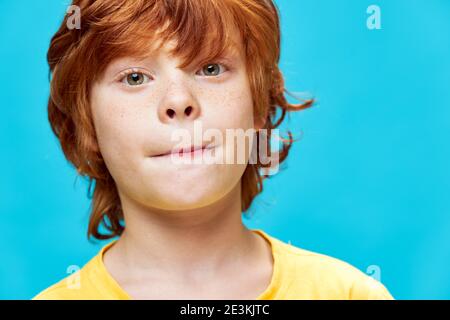 Cute redhead boy face closeup freckles yellow t-shirt cropped view  Stock Photo