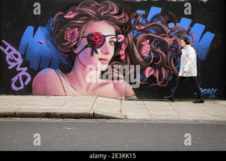 London, UK. 19 January 2021. Street Art London. A woman walks past a mural painted by the artist Irony in Camden Town. Credit: Waldemar Sikora Stock Photo