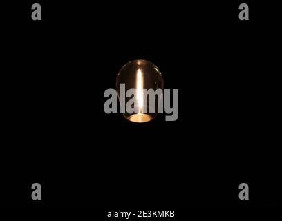 an illuminated edison light bulb on a black background Stock Photo