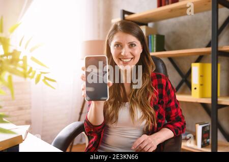 Happy woman shows something in her modern smartphone Stock Photo