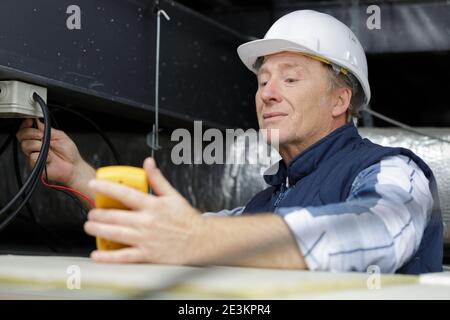 senior electrotechnician connecting wiring system Stock Photo
