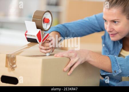 close-up of female sealing cardboard box with adhesive tape Stock Photo