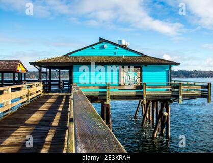 Turquoise building on pier in Campbell River, BC.  Wooden walkway on a sunny day.  Colorful building, blue sky and some clouds. Stock Photo