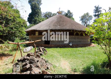 The xterior of the Azewa Mariam monastery, its Ethiopian Orthodox cross and thatched roof basking in the sunlight of a clearing near Bahir Dam, Ethiop Stock Photo