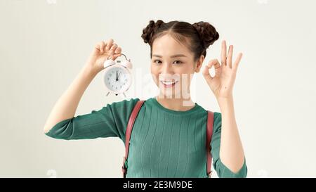 Young beautiful woman holding vintage alarm clock over isolated white background doing ok sign with fingers, excellent symbol Stock Photo