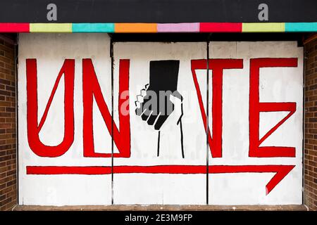 Painted mural on boards over a storefront window asking for unity during the civil unrest after the killing of George Floyd in Minneapolis, Minnesota Stock Photo
