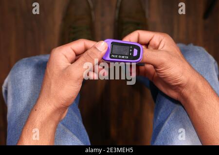man sitting on chair using pulse oximeter, top view  Stock Photo