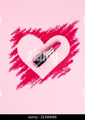 Valentine's Day background. Red and pink lipstick smeared in the shape of heart. Isolated on pink background. Cosmetic products Stock Photo
