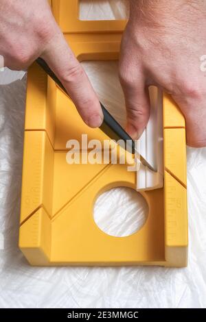 The man cuts off the molding cornice on the miter box. Stock Photo