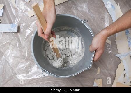 Mixing white plaster in a bucket with a stirrer. Close-up. Stock Photo