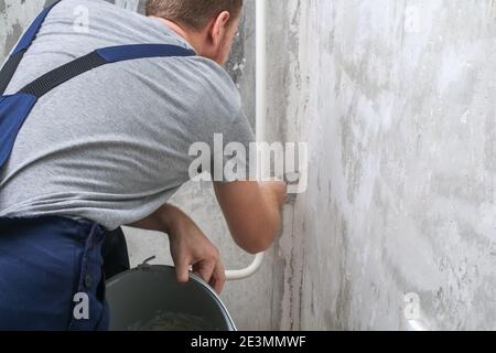 The man is plastering the walls in the room. Close-up. Stock Photo