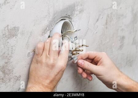 A man dismantles and mends an electrical outlet for repairs. Power socket. Stock Photo