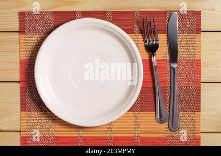 Cutlery and empty plate on bamboo napkin, top view Stock Photo