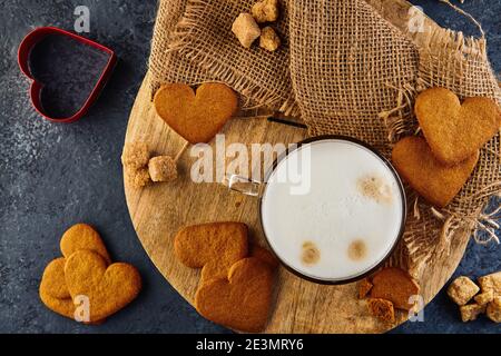 Heart shaped gingerbread cookies with a cup of cappuccino coffee on a wooden board. Flat lay Stock Photo