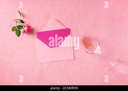Greeting card, Valentine or invitation mockup, a flat lay with a pink rose and rose wine, top shot on a pink background Stock Photo