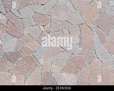 A wall with decorative cladding lined with granite pieces of tiles of different shapess Stock Photo