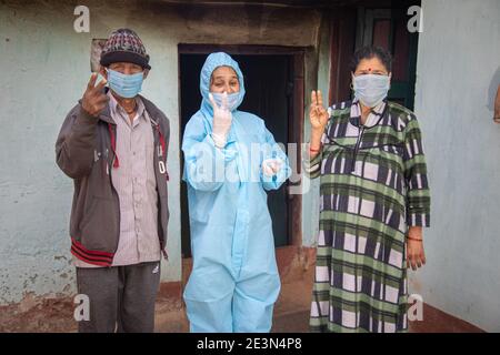 Young woman doctor in medical uniform holding a syringe and coronavirus vaccine, standing with village man and women explaining importance of corona v Stock Photo
