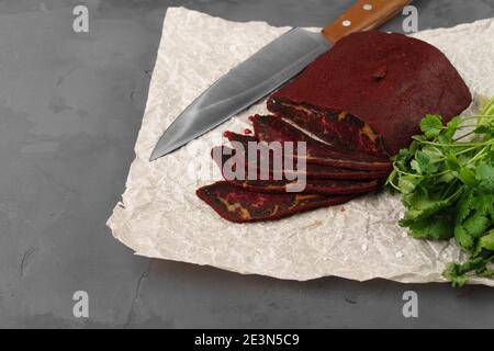 Cut basturma meat product with parsley on parchment Stock Photo