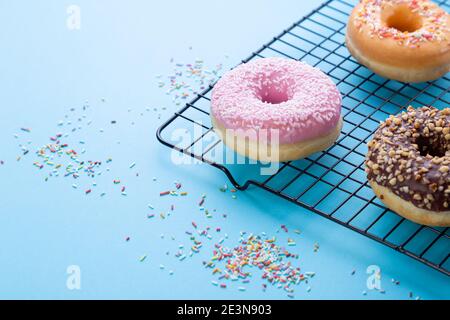 Mixed donuts on grid on blue background. With copy space. Stock Photo