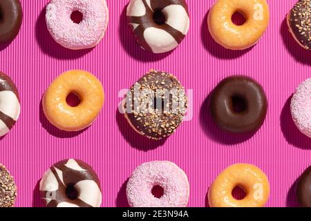 Flat lay composition of mixed donuts on pink background. Stock Photo