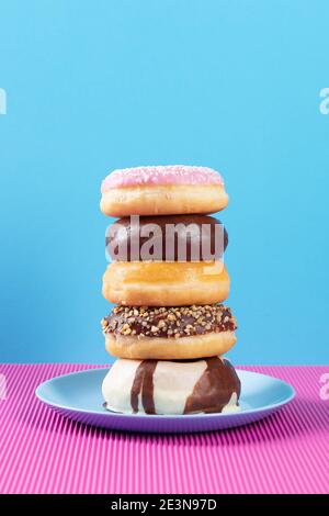 Stack of diferent donuts on pink and blue background. Stock Photo
