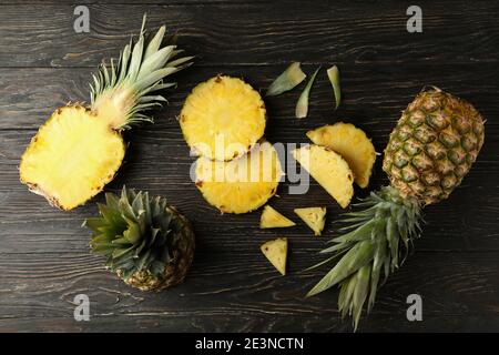Ripe pineapples cut into slices on dark wood in a top view, a tropical pineapple flat lay with juicy golden rings Stock Photo