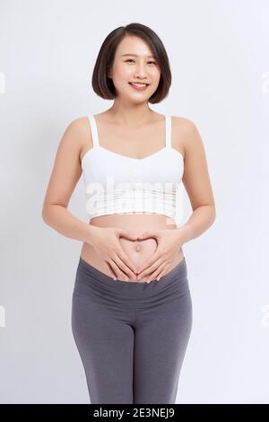 Pregnant woman standing and holding her hands in form of heart sign on her belly Stock Photo