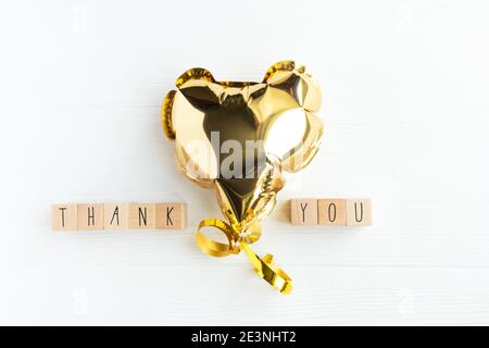 The word thank you on wooden cubes and a heart shaped balloon on a light background with space for text. Stock Photo