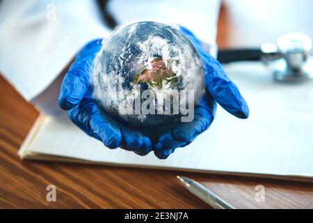 Doctor holding a world globe in hands, concept of world health, supporting, prevention and protection against coronavirus pandemic woldwide. Planet Earth. Saving nature and environment, travel. Stock Photo