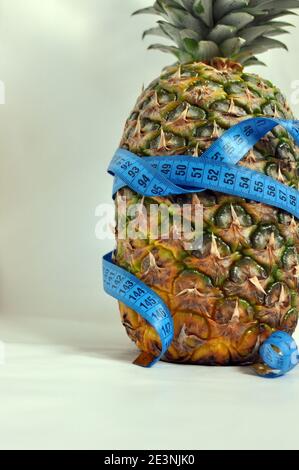 Pineapple wrapped with blue tailoring meter on white background, close up Stock Photo
