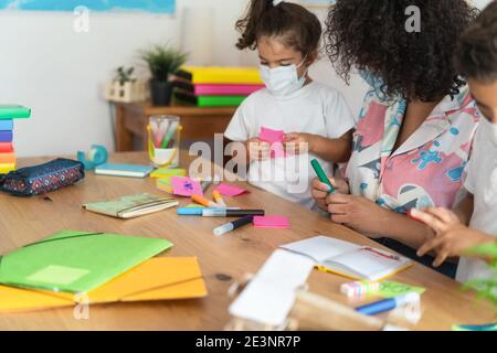 Teacher working with children inside preschool while wearing safety masks - Focus on woman hand Stock Photo