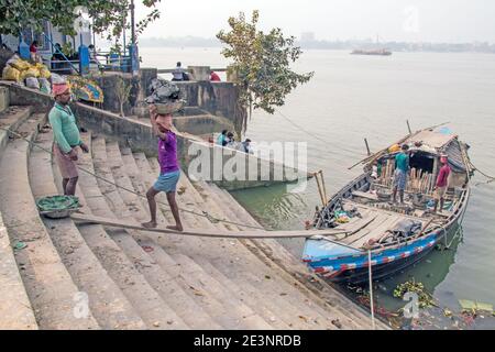 The silt for making idols is being unloaded from a boat at Kumortuli ghat. The ideal silt for making idols is river soil which is taken from kolaghat. Stock Photo