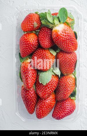 Transparent plastic tray, with freshly picked strawberries, on white background, top view flat lay Stock Photo
