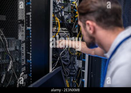 Man near open server rack fingering wires Stock Photo