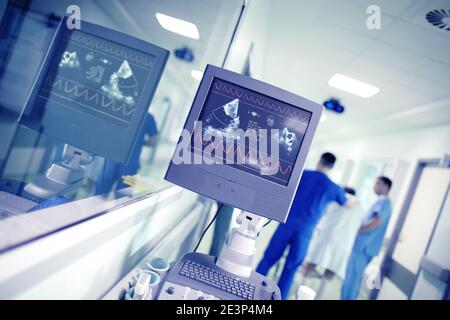 Cardiac activity monitoring on the background of talking male doctors in the hospital corridor. Stock Photo