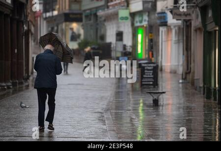 A person uses an umbrella as they walk in the rain up the High street in Winchester, Hampshire as Storm Christoph is set to bring widespread flooding, gales and snow to parts of the UK. Heavy rain is expected to hit the UK, with the Met Office warning homes and businesses are likely to be flooded, causing damage to some buildings. Picture date: Wednesday January 20, 2021. Stock Photo