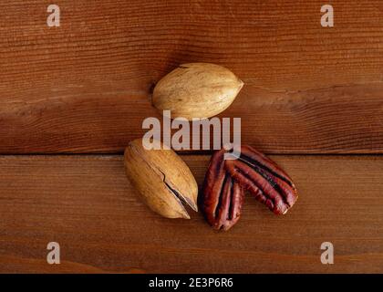 Heap of pecans in shell and decorticated peeled nut on wooden table. Top view Stock Photo