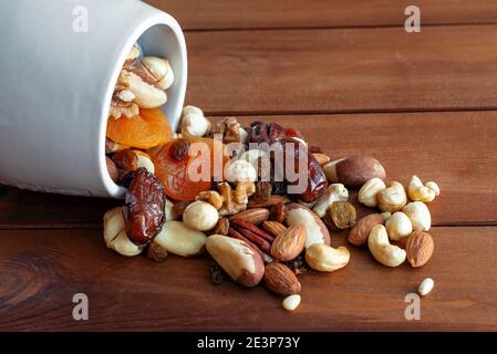 Scattered mixed nuts and dried fruit on dark wooden background. Healthy food and snack Stock Photo